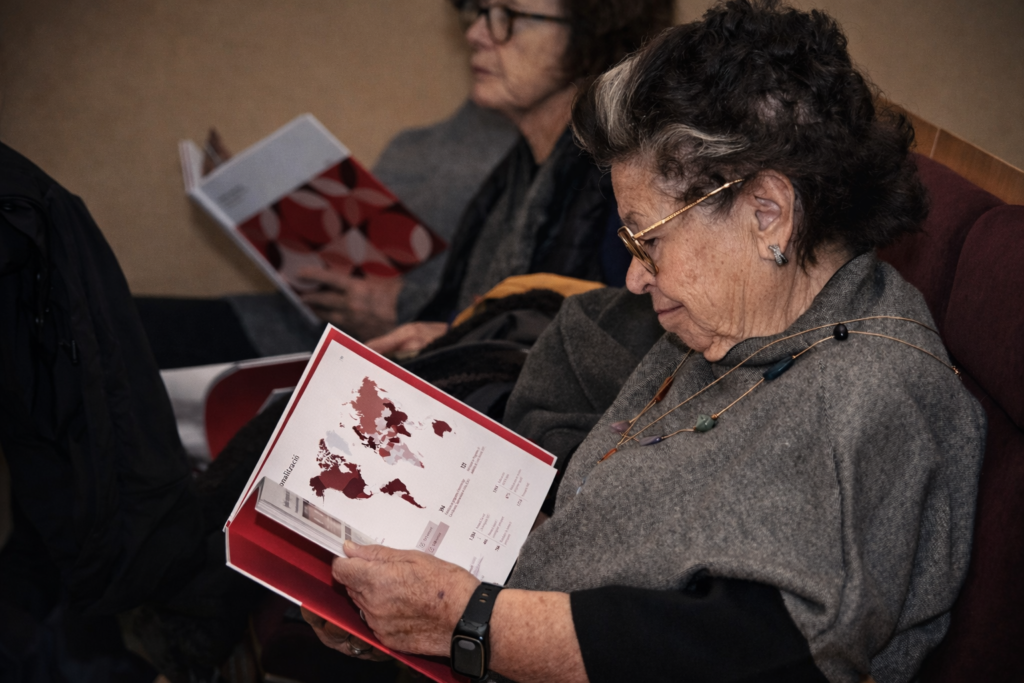 Dues dones assegudes en una sala d'actes a Tortosa consultant el llibre del 30è aniversari del Consell Social de la URV.