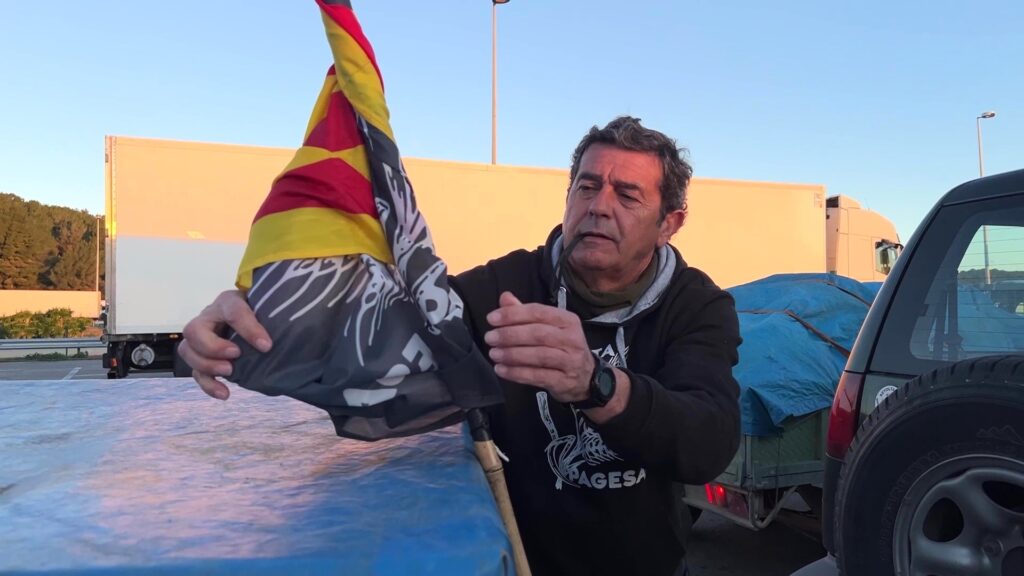 Un pagès preparant una bandera de la Revolta Pagesa a les Terres de l'Ebre durant una concentració a l'AP-7.