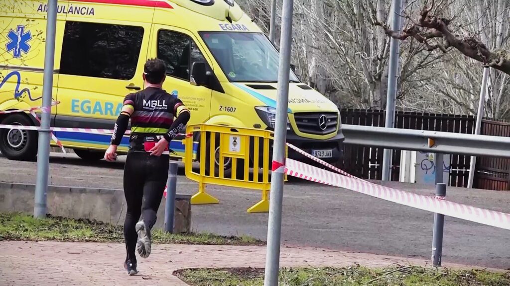 Atleta corrent per un camí a Garcia prop d'una ambulància d'Egara durant la Duatló de la Ribera d'Ebre.