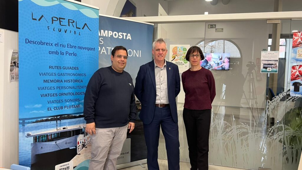 Representants municipals d'Amposta presentant el balanç turístic del 2025 davant el cartell de La Perla Fluvial al Montsià.