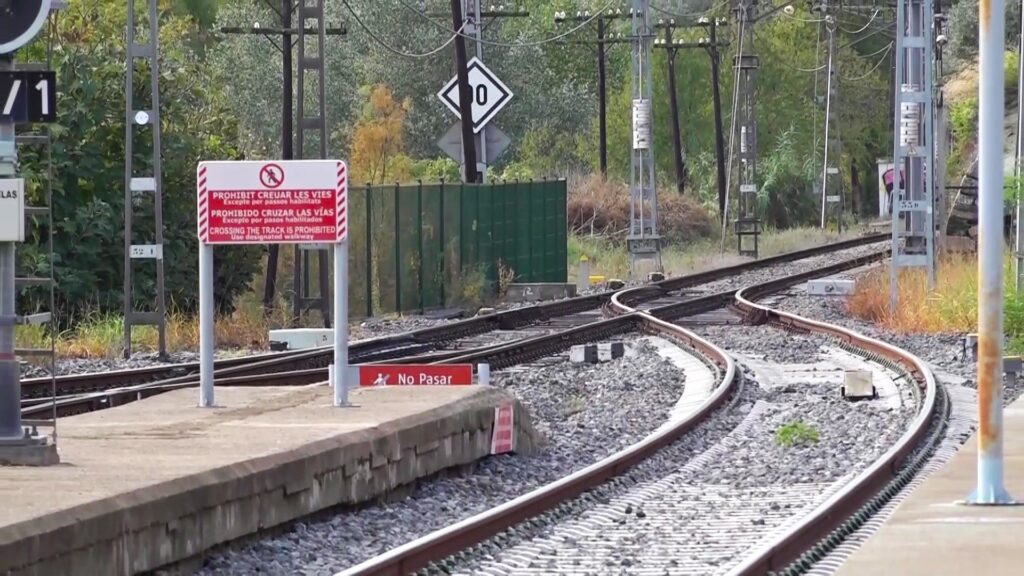 Vies del tren i canvi d'agulles en una estació ferroviària a les Terres de l'Ebre amb senyalització de prohibit creuar.