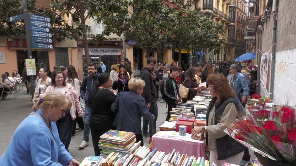 Gent passejant i comprant llibres a les parades de Sant Jordi al carrer de la Rosa de Tortosa, Baix Ebre.