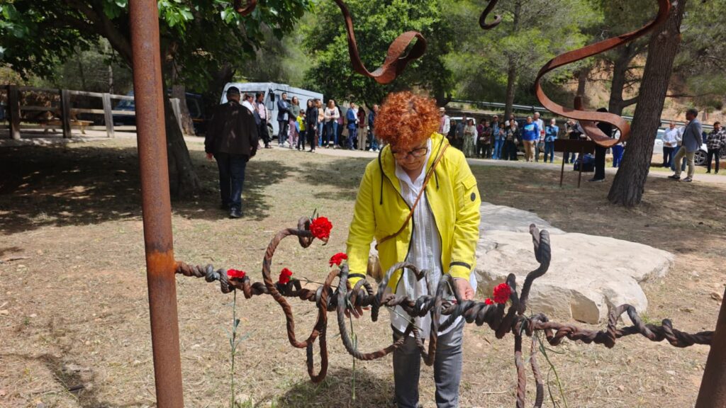 Una dona col·loca un clavell roig en el monòlit de record als deportats de la Terra Alta a Prat de Comte.