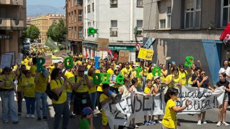 Manifestació de docents en vaga en un carrer de Tortosa amb samarretes grogues i lletres verdes que formen la paraula "Protestes".