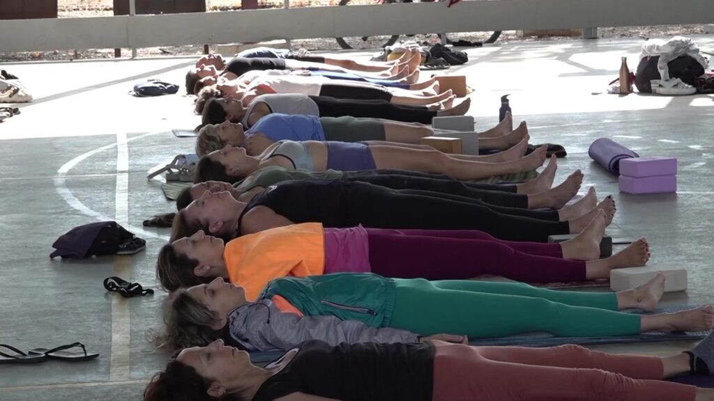 Participants estesos a terra fent ioga en una sessió col·lectiva al Poblenou del Delta durant el festival Lo Yogafest.