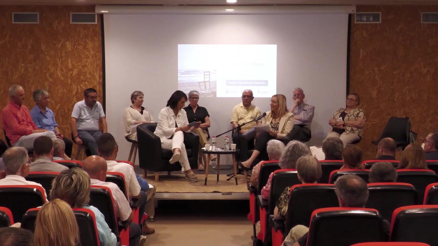 Diversos testimonis i familiars asseguts a l'escenari compartint relats durant l'Audiència Memorial a Benifallet.