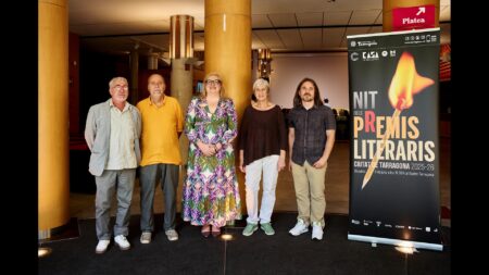 Participants i organitzadors de la Nit dels Premis Literaris Ciutat de Tarragona davant del cartell oficial