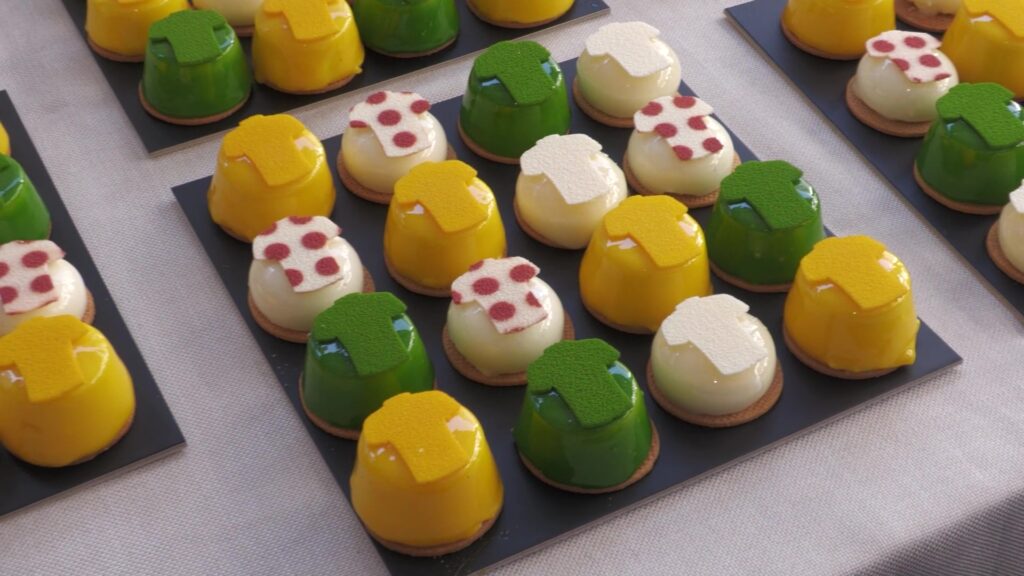 Pastissos artesanals de colors grog, verd, roig i blanc inspirats en els mallots del Tour de França estesos sobre una taula a Amposta, Terres de l'Ebre.