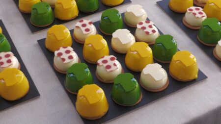 Pastissos artesanals de colors grog, verd, roig i blanc inspirats en els mallots del Tour de França estesos sobre una taula a Amposta, Terres de l'Ebre.