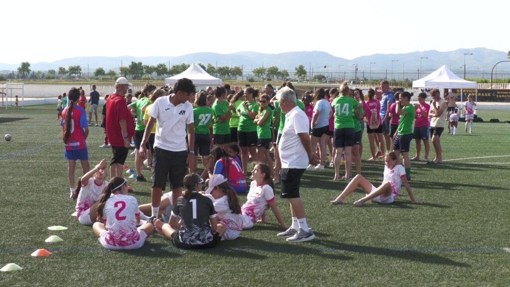 Jugadores i entrenadors de futbol femení sobre el camp de gespa artificial a Roquetes durant la Woman's Champions Cup.