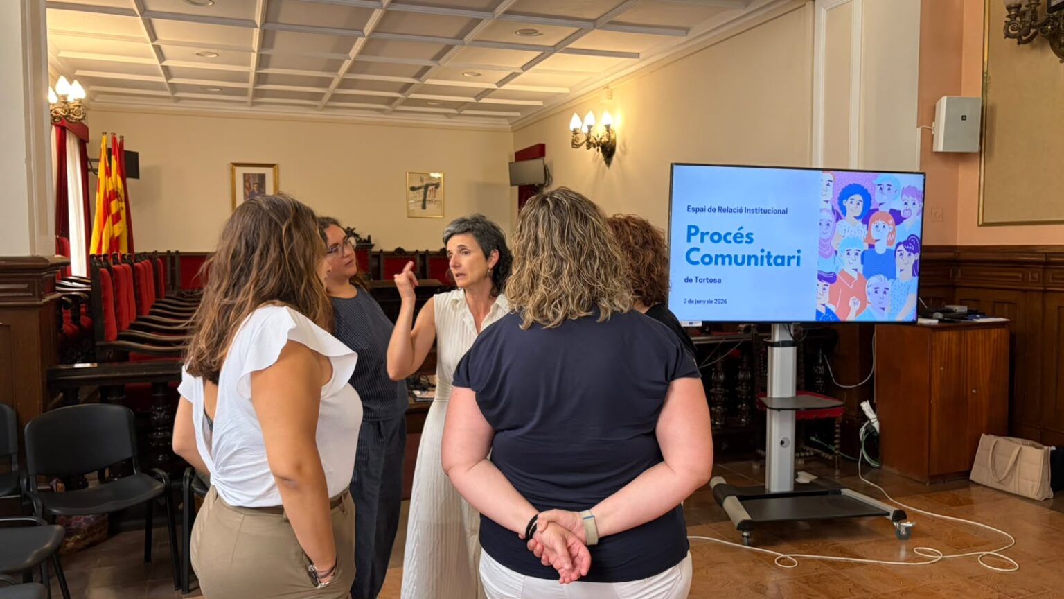 Representants institucionals i tècnics del Procés Comunitari conversen al saló de sessions de l'Ajuntament de Tortosa.