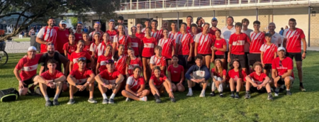 Membres de l'equip del Club de Rem Tortosa vestits amb l'equipació de color roig posant junts sobre la gespa durant el Campionat de Catalunya a Banyoles.