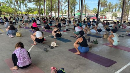 Participants fent exercicis de ioga al pavelló poliesportiu del Poblenou del Delta durant el Loyogafest.