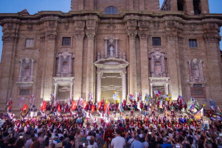 Acte inaugural de la Festa del Renaixement de Tortosa a la portalada barroca de la catedral amb banderes i personatges vestits d'època davant del públic.