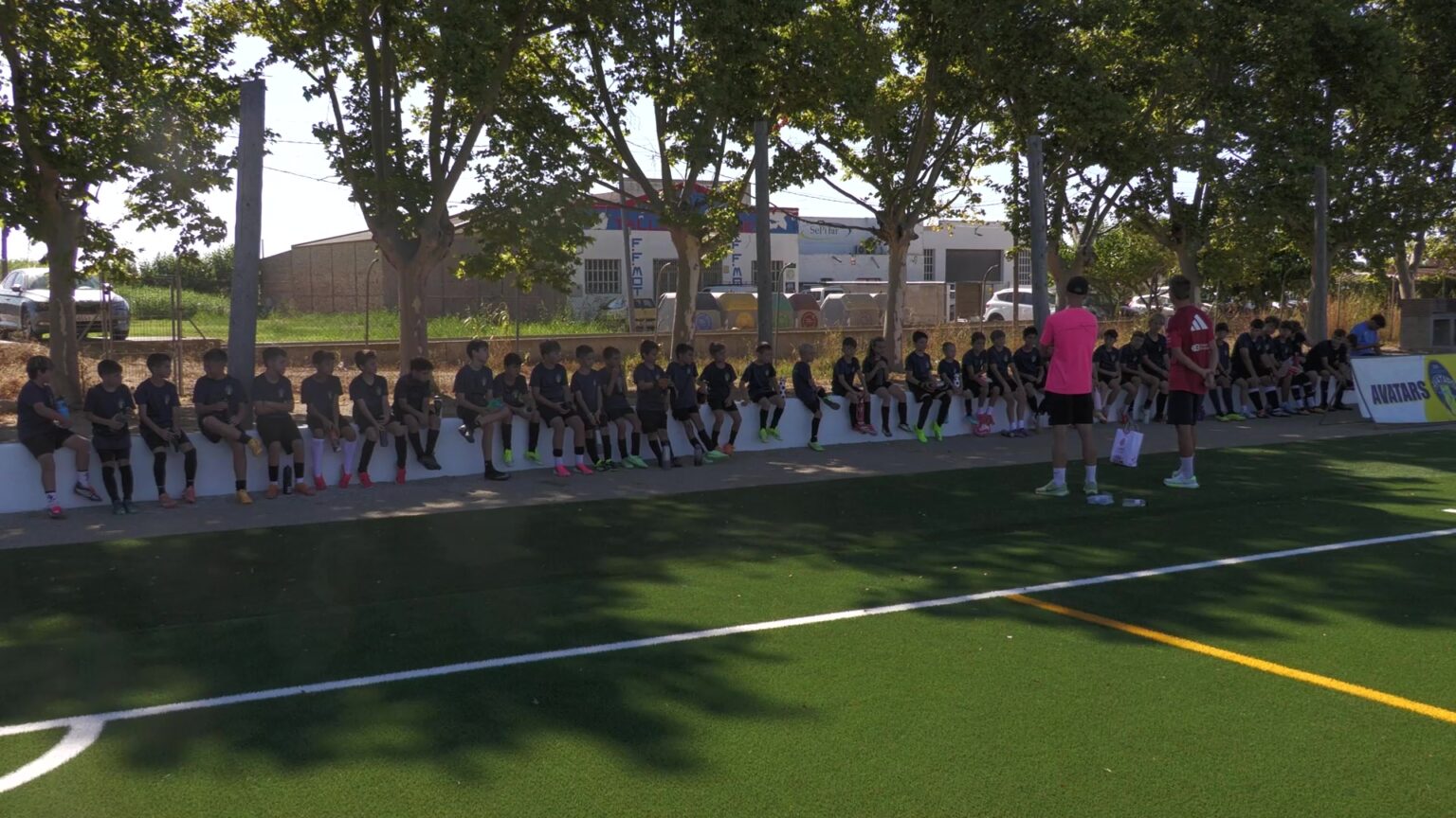 El Campus Avatars reforça la tecnificació i els valors amb la mirada posada en el futur del futbol ebrenc Jóvens jugadors del Campus Avatars asseguts a la graderia de gespa artificial del camp de futbol a Deltebre, Baix Ebre, escoltant les indicacions dels entrenadors.