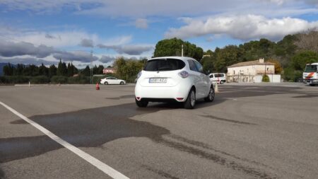Vehicle d'autoescola blanc realitzant pràctiques en una esplanada amb cons