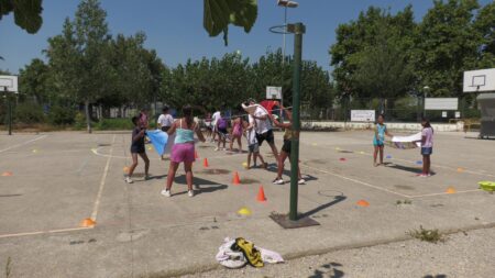 Infants fent dinàmiques de joc cooperatiu en grup a la pista exterior d'un centre escolar d'Amposta, al Montsià.
