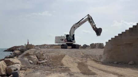 Excavadora treballant a les obres del dic del port de les Cases d'Alcanar