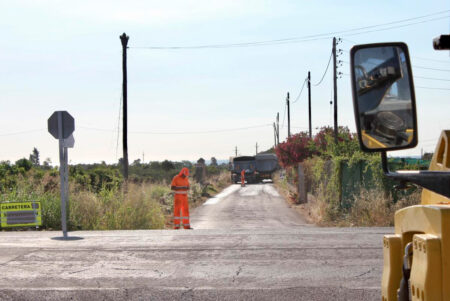 Operaris i maquinària pesant estenent una nova capa d'asfalt en un tram afectat del camí de Virol a Alcanar, Montsià.