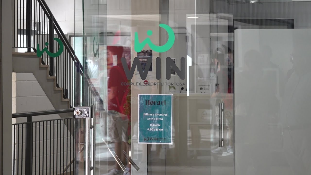 Tortosasport aparta un monitor del casal esportiu del WIN després de dues denúncies per presumptes abusos o maltractaments Porta d'accés de vidre al complex esportiu WIN Tortosa amb el logotip verd i un cartell amb l'horari d'obertura.